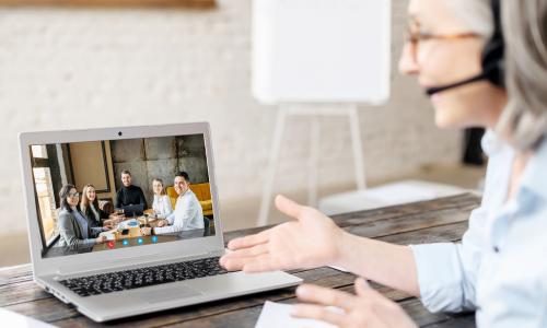 senior executive uses laptop to videoconference with a team