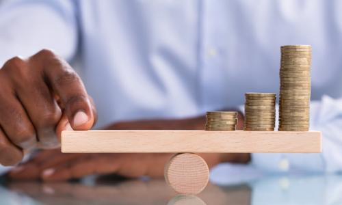 businessman balancing coin stack on wooden beam