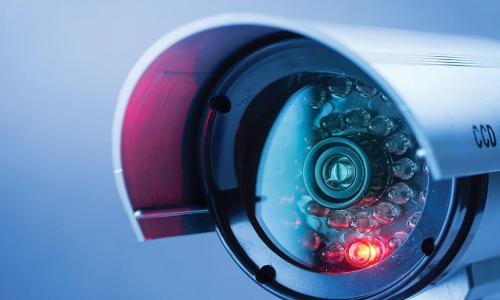 closeup of sleek security camera with red recording light on