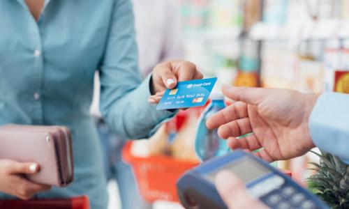 woman uses her credit card to check out at the grocery store