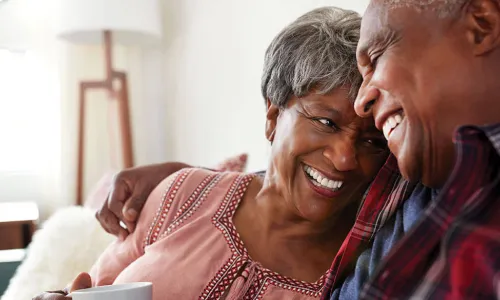 happy retired Black couple with arms around each other at home