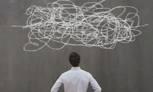 businessman studies squiggle of complexity drawn on chalkboard