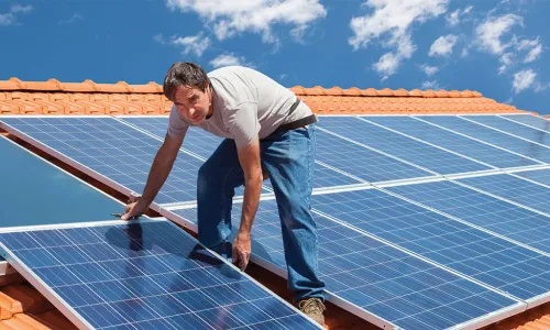 roofer installing solar panels on a terra cotta tile roof