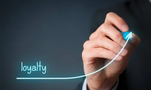 businessman's hand writing loyalty and drawing a line under it that trends upward