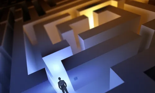 usinessman stands at entrance to maze with sections in both shadows and bright light