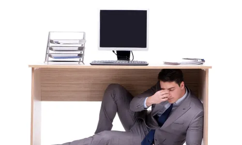 stressed tired business manager hiding under office desk