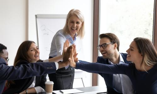 diverse team of celebrating young employees high five with manager