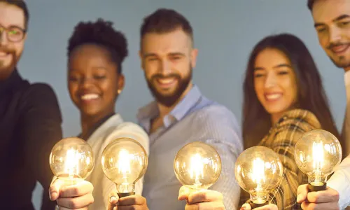 Group of young businesspeople holding up glowing lightbulbs