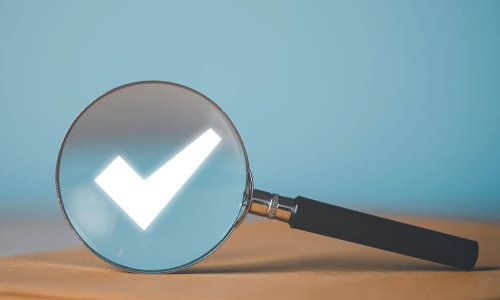 magnifying glass on desk looking at a glowing white checkmark