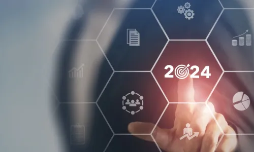 Businessman touching a 2024 business target icon with other icons floating on a screen around it