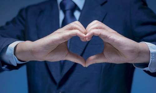 hands making heart symbol in front of man in suit