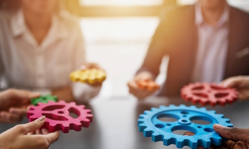 hands bringing gears together at a table