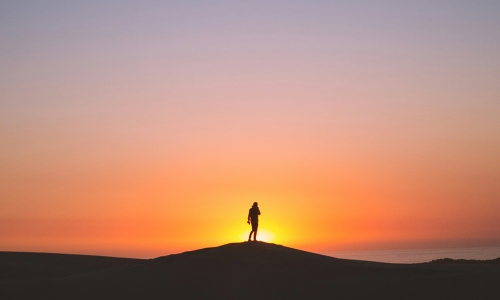 person silhouetted in front of a sunrise