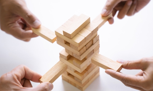 four hands playing Jenga game