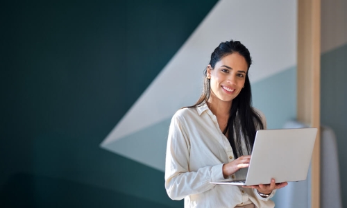 smiling woman standing holding a laptop