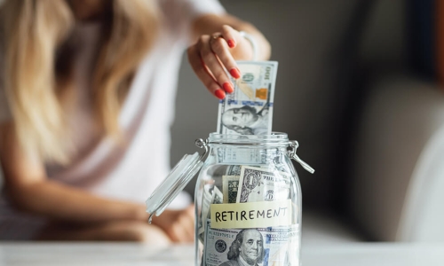 woman putting one hundred dollar bill in a jar marked Retirement