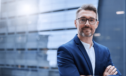 man standing in front of window with arms crossed and a smile on his face