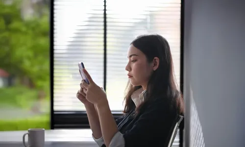 woman sitting at a table looking at her cell phone