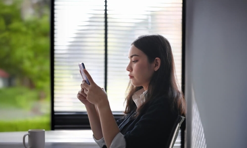 woman sitting at a table looking at her cell phone