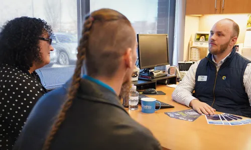 a couple speaking with a Telhio employee at his desk