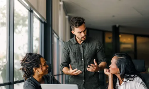 3 individuals talking behind a laptop