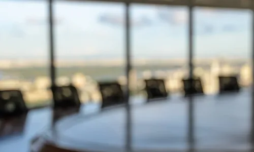 blurry image of board room table chairs with windows in background