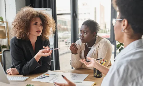 3 women having a discussion at a desk 